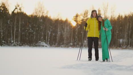A-man-embraces-a-woman-standing-in-the-woods-at-sunset-after-a-winter-walk-on-skis.-St.-Valentine's-Day.-Romance-and-warm-feelings-of-lovers.-Slow-motion